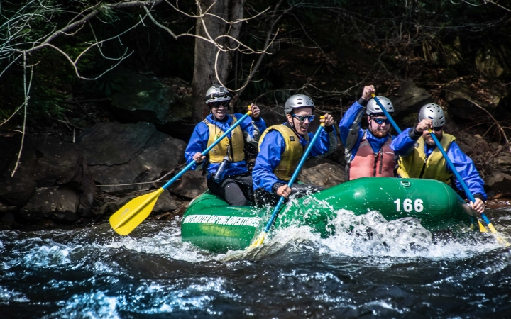 a group of veterans paddle a raft on an outward bound course
